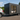 Modular building on wheels next to a car with trees in the background