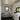 Small living space with a bed, kitchenette, and windows.