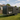 Portable container home on trailer on a grassy area with a house in the background